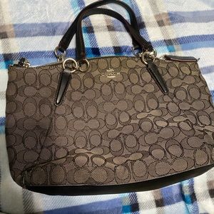 This is a black Coach purse with the Coach logo pattern.